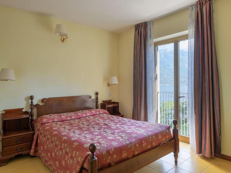 Sypialnia z podwójnym łóżkiem, drewnianymi meblami i balkonem z widokiem na góry.