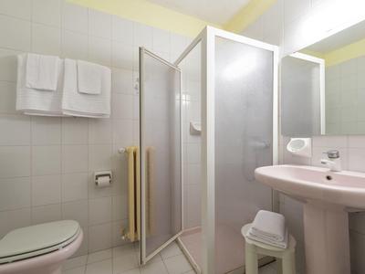 Petite salle de bain avec douche, lavabo, toilettes et serviettes accrochées au mur.