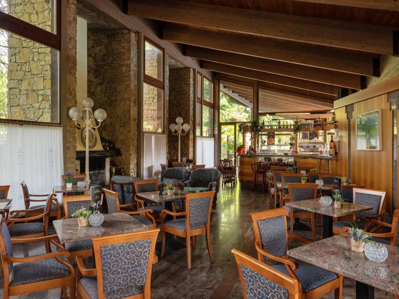 Salle à manger d'hôtel confortable avec poutres en bois, cheminée en pierre et tables avec dessus en marbre.