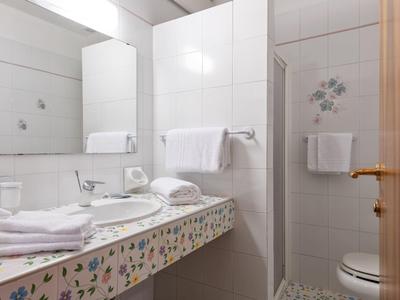 Schone badkamer met wastafel, spiegel, handdoeken en douchecabine.