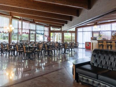 Grande salle à manger d'hôtel avec de nombreuses tables, chaises et un coin salon confortable.