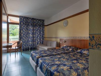 Chambre d'hôtel avec deux lits, canapé, bureau et vue sur un balcon