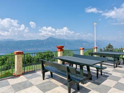 Terras met zwarte banken en tafels met uitzicht op bergen en meer onder een heldere lucht