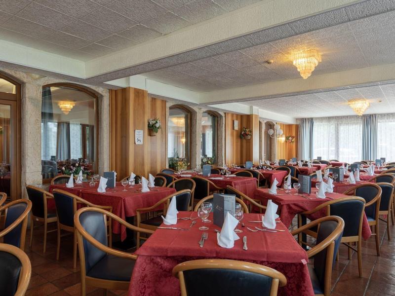 Sala da pranzo elegante con tovaglie rosse, decorazioni e sedie confortevoli.