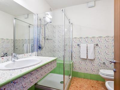 Bagno luminoso con doccia, lavandino, specchio e piastrelle decorate.