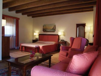 Camera d'hotel accogliente con travi in legno, mobili rossi e lampade da tavolo.