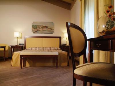 Camera d'hotel accogliente con letto, sedia, tavolo e decorazioni sotto luce calda.