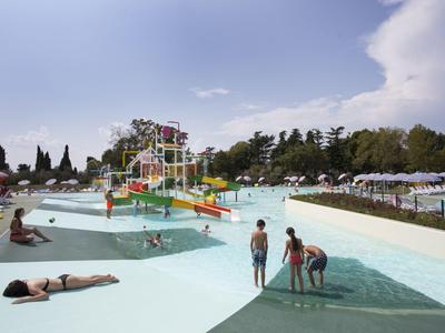 Outdoor-Wasserpark mit Wasserrutschen und Menschen, die im flachen Pool entspannen.