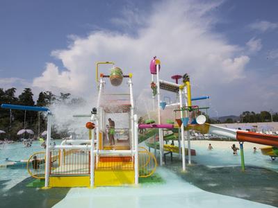 Kinder spielen auf einer farbenfrohen Wasserrutsche im Pool mit blauem Himmel im Hintergrund.