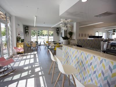 Modernes Café mit weitem Fenster, hellem Interieur und buntem Tresen im Reiseambiente.