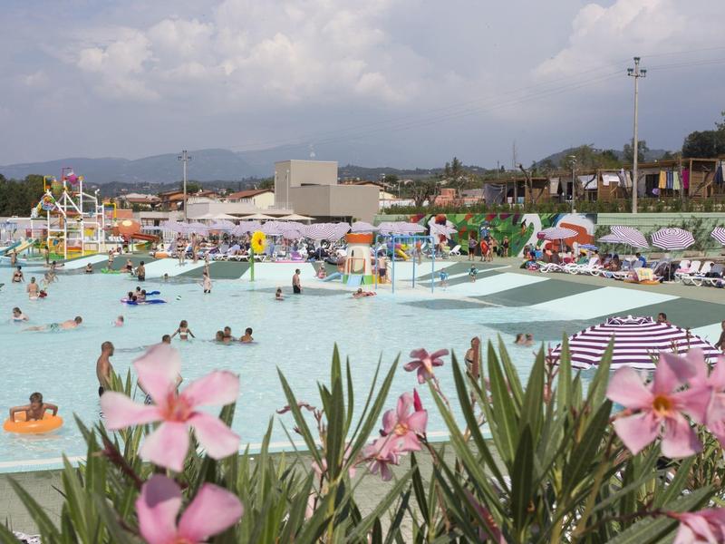 Freizeitbad mit vielen Menschen, großen Pools, Wasserrutschen und Blumen im Vordergrund.