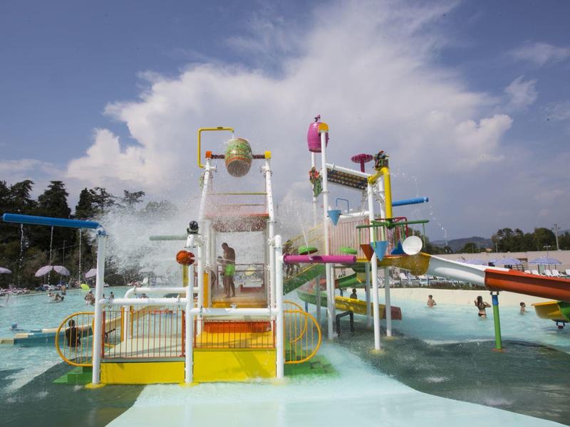 Wasserpark mit Rutschen, Becken und bunten Spielgeräten unter blauem Himmel.