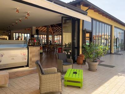 Außenbereich eines Cafés mit Stühlen, Tischen und großen Fenstern bei Tageslicht.