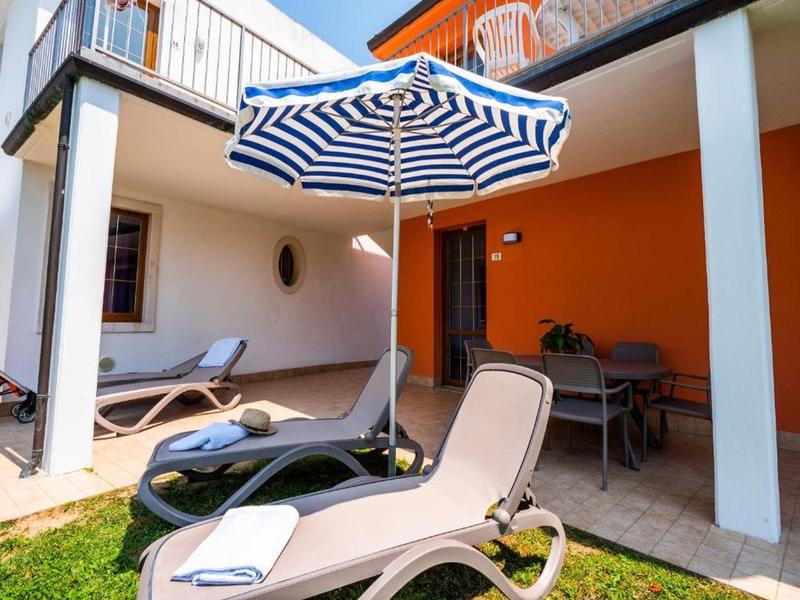 Lettini con ombrellone blu e bianco su una terrazza d'hotel con parete arancione.