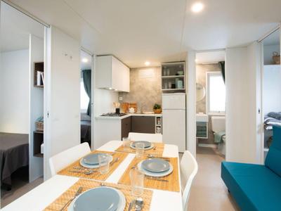 Moderner Hotelzimmerbereich mit Küche, Essplatz und angrenzendem Schlafzimmer.