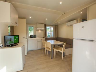 Světlá moderní kuchyň a jídelní prostor s lednicí, stolem, židlemi a pohovkou.