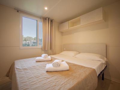 Pohodlný dvoulůžkový pokoj s postelí, závěsy a ručníky u okna.