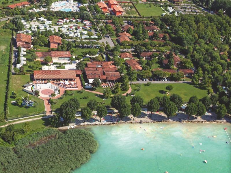 Letecký pohled na rezort s bazénem, budovami a břehem u čistého jezera.