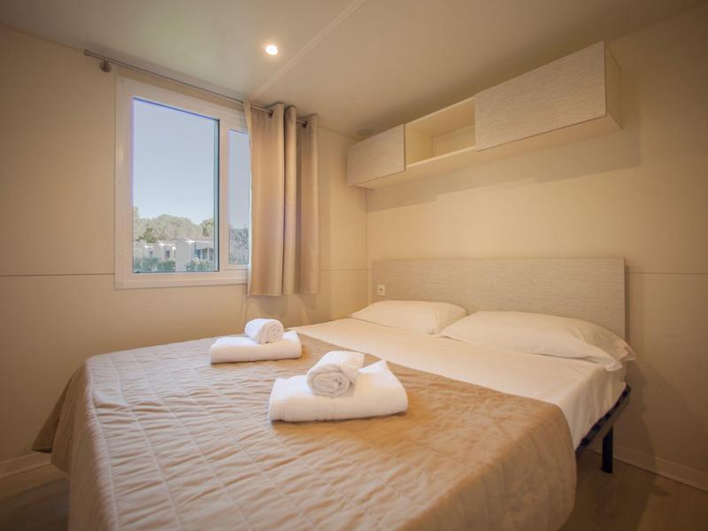 Pohodlný dvoulůžkový pokoj s postelí, závěsy a ručníky u okna.