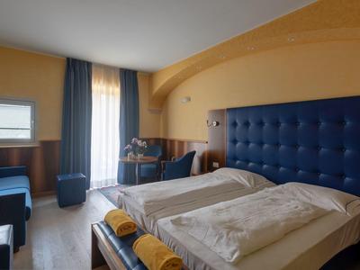 Cozy hotel room with two single beds, blue accents, and a window with curtains.