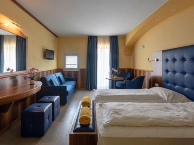 Cozy hotel room with double bed, sofa, TV, and desk in warm tones.