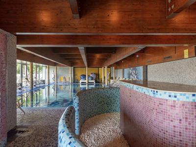 Innenansicht eines Hotelschwimmbads mit runden Becken und Holzbalkendecke