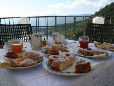 Frühstückstisch mit Gebäck und Getränken auf Balkon mit Bergblick