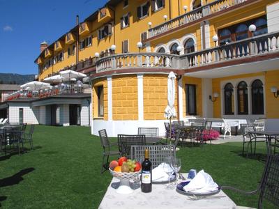 Hotelterrasse mit gelbem Gebäude, gedecktem Tisch und grüner Rasenfläche bei blauem Himmel