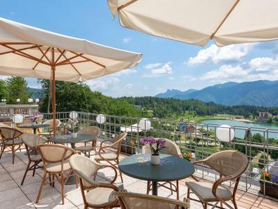 Terrace with tables, chairs, and umbrellas overlooking mountains and a river.