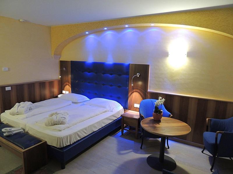 Modern hotel room with double bed, seating area, and relaxed lighting.