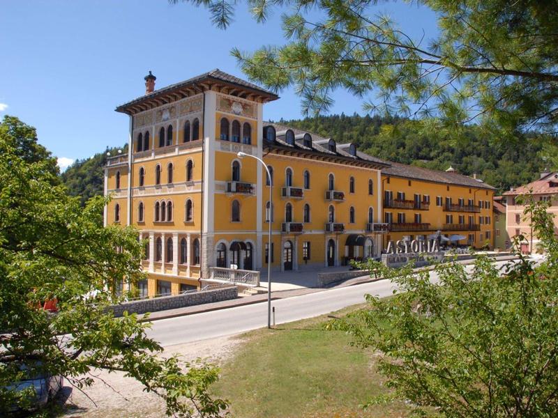 Yellow multi-story hotel building in green surroundings under a blue sky.