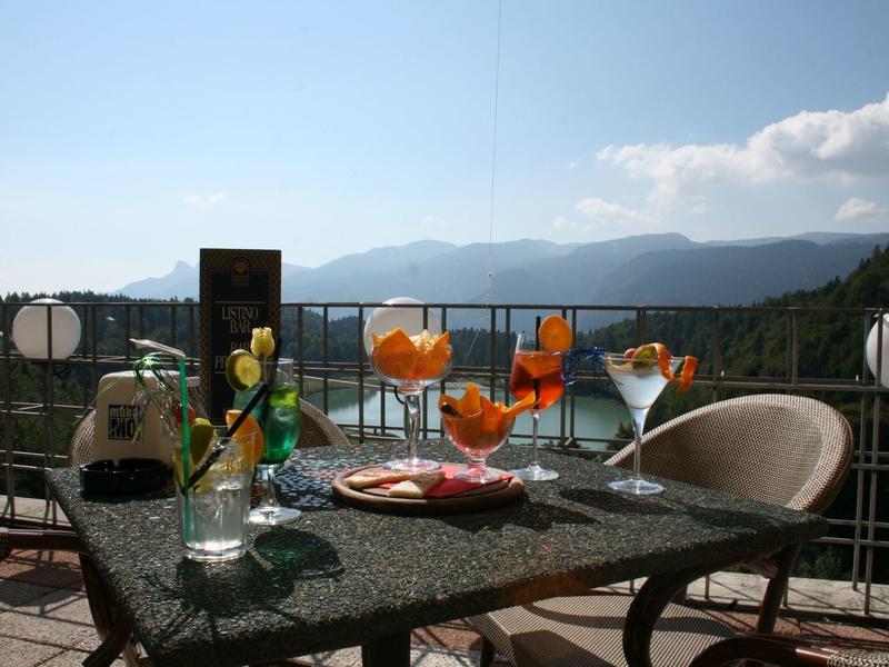 Balcony table with drinks and snacks overlooking mountains on a sunny day.
