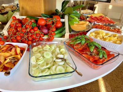 Buffet met verse groenten zoals tomaten, komkommers, paprika's en vruchtenslices.