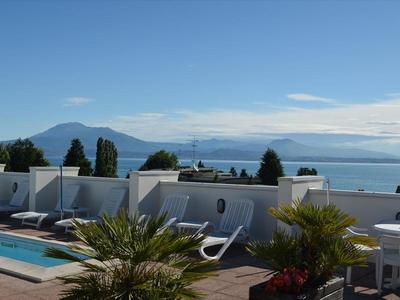 Dakterras met zwembad, planten en uitzicht op bergen en meer onder heldere lucht