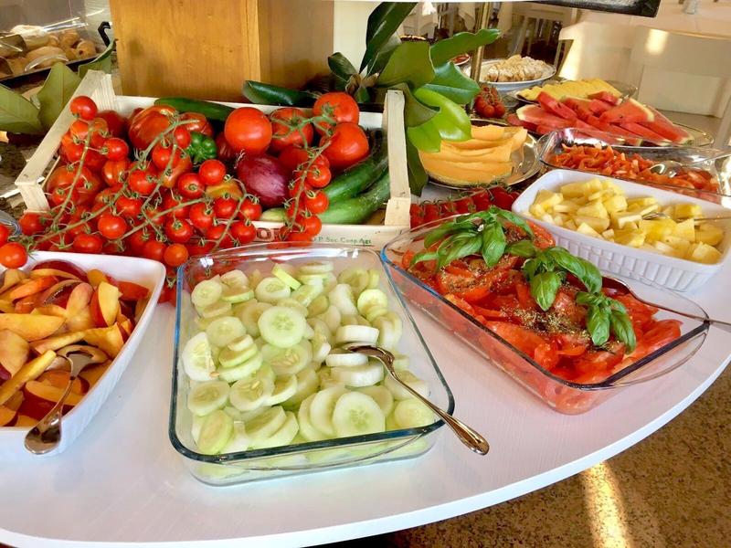 Buffet met verse groenten zoals tomaten, komkommers, paprika's en vruchtenslices.