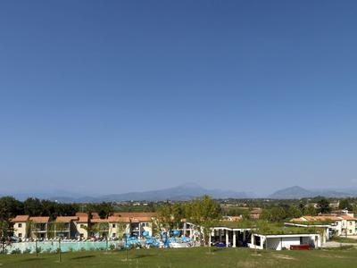 Reihenhäuser und Wiesen unter klarem, blauem Himmel mit Bergen am Horizont.