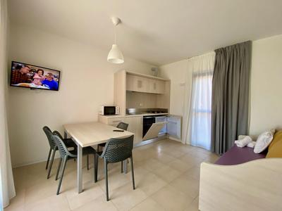 Moderner Küchen- und Essbereich mit grauen Stühlen und Fernseher an der Wand.