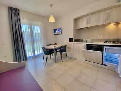 Helle Hotelküche mit moderner Ausstattung und Esstisch vor bodentiefen Fenstern und Balkon.