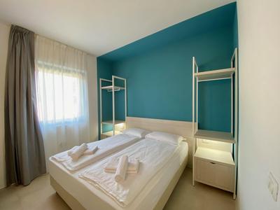 Modernes Hotelzimmer mit Doppelbett, blauer Akzentwand und natürlichem Licht vom Fenster.