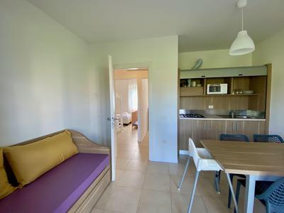 Moderner Essbereich mit Holztisch, weißen Stühlen und Zugang zu einer Küche im Hotelzimmer.