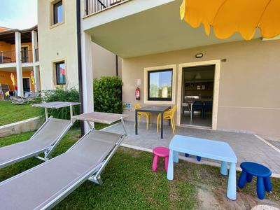 Terrasse mit Liegestühlen und buntem Kinderspielzeug vor Hotelzimmer.