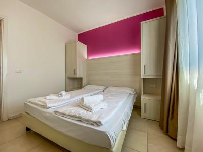 Schlichtes Hotelzimmer mit Doppelbett, weißen Handtüchern und natürlichem Tageslicht.