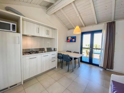 Moderner Küchenbereich mit Esstisch und Zugang zu Balkon in hell eingerichteter Ferienwohnung.