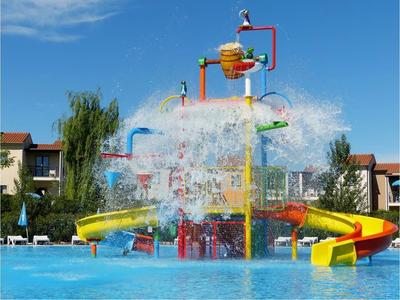 Wasserpark mit großen, bunten Rutschen, spritzendem Wasser und blauem Himmel.