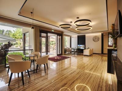 Heller, moderner Wohnraum mit Holzfußboden, Essbereich, Sofa und großen Fenstern mit Blick ins Grüne.