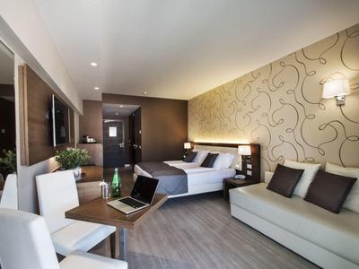 Nowoczesny pokój hotelowy z łóżkiem, sofą, biurkiem i telewizorem.