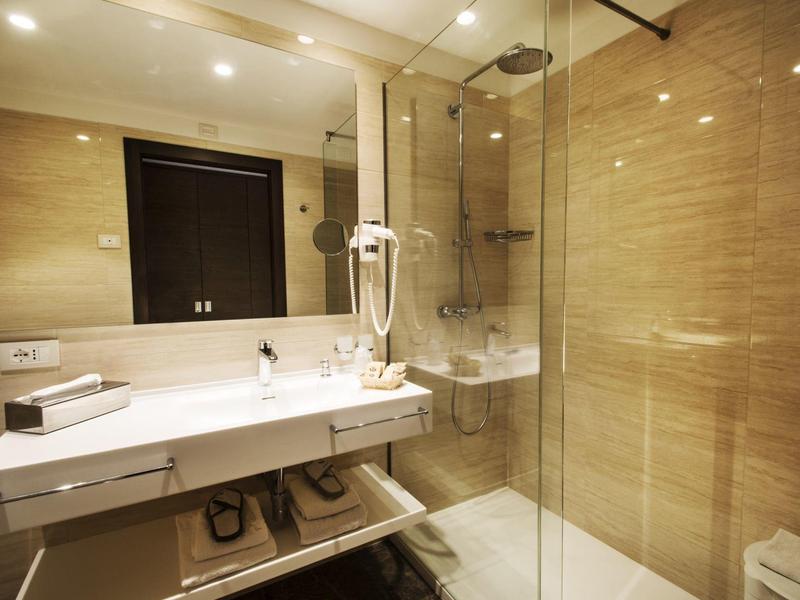 Jasna łazienka z dużym lustrem, kabiną prysznicową i nowoczesną umywalką.