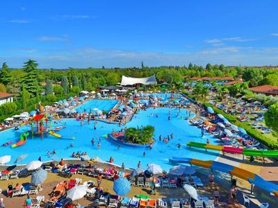 Großer Freibadkomplex mit Wasserrutschen, Liegestühlen und Menschen bei sonnigem Wetter