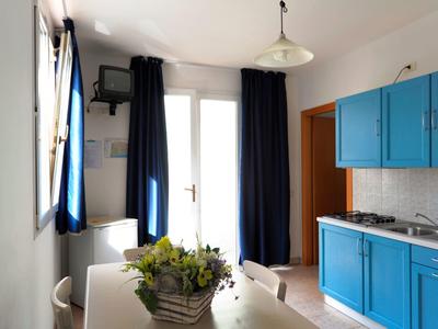 Bright kitchen with blue cabinets, white table, and dark curtains