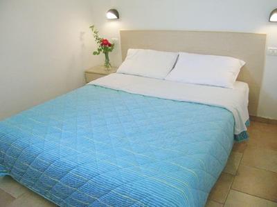 Simple hotel room with bed, blue quilt, and nightstand with flowers.